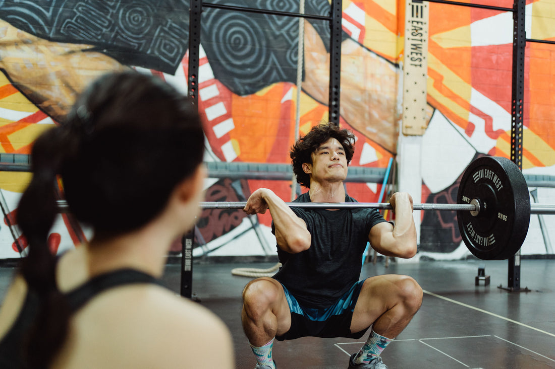 Man performing a weighted squat at the gym, illustrating research on grounding and muscle recovery